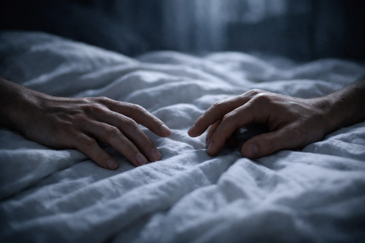 Close-up of two men’s hands almost touching on a white duvet, capturing pining in gay romance books.