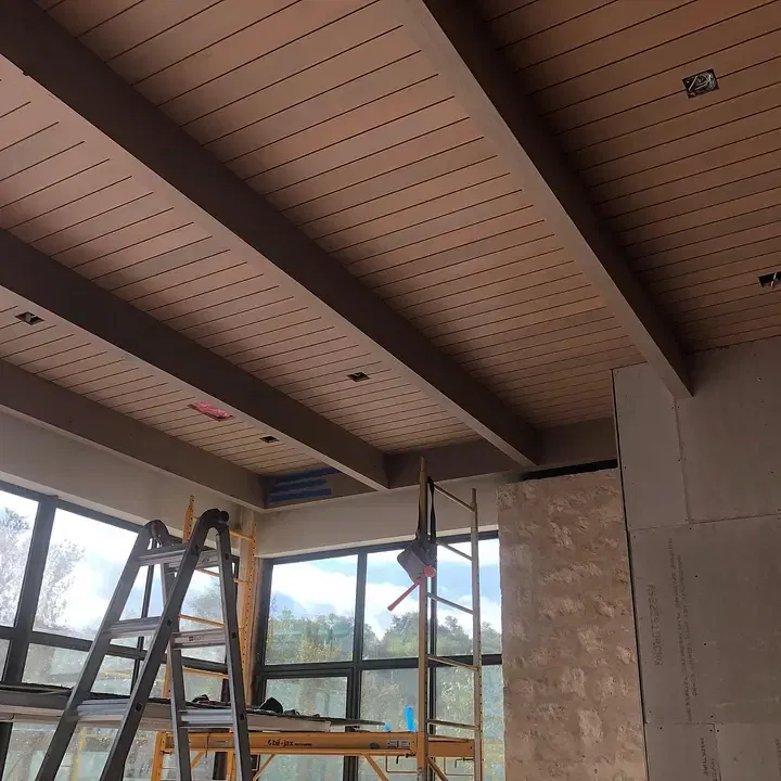 Meticulously painted modern tongue-and-groove wood ceiling with exposed beams in a high-end residential living area.