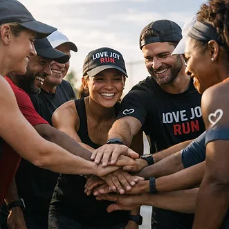 A diverse group of runners in LOVE JOY RUN apparel share a team huddle