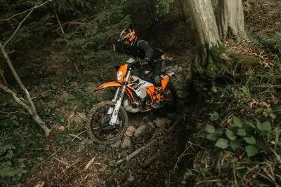 The Ultimate Guide to Off-Road Vehicles in Reno: Everything You Need for Tahoe Trails 1 A rider navigates a rugged forest trail on an orange KTM dirt bike, showcasing the agility needed for Northern Nevada trails.