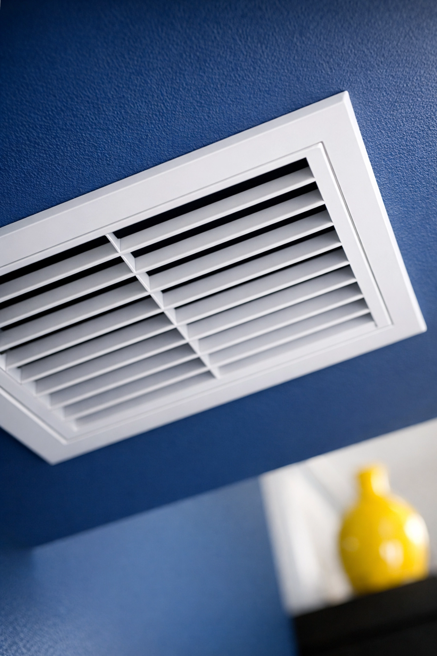 Clean modern HVAC vent on a blue wall, preventing dust buildup in residential cleaning Leominster MA homes.