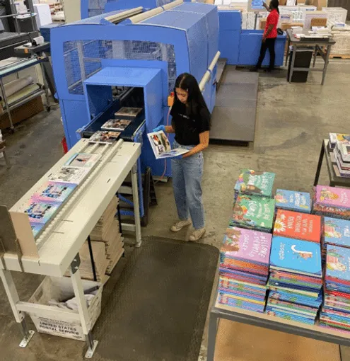 Digital book production line showing an operator inspecting freshly printed children’s books