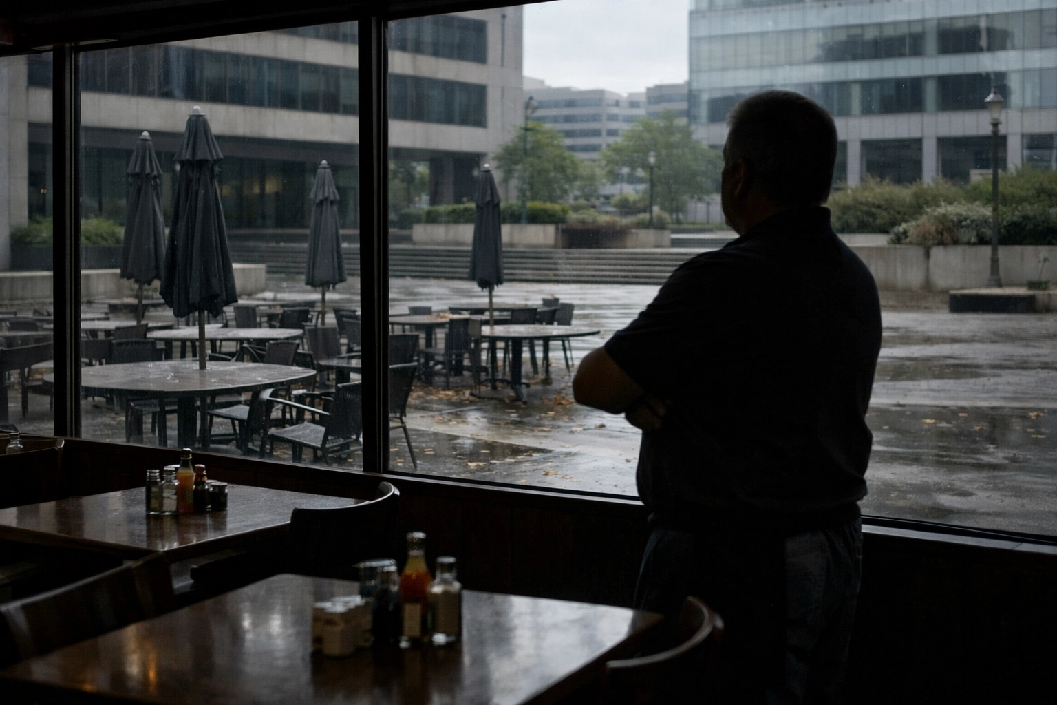 Restaurant owner viewing empty outdoor dining area after losing anchor tenant customer base