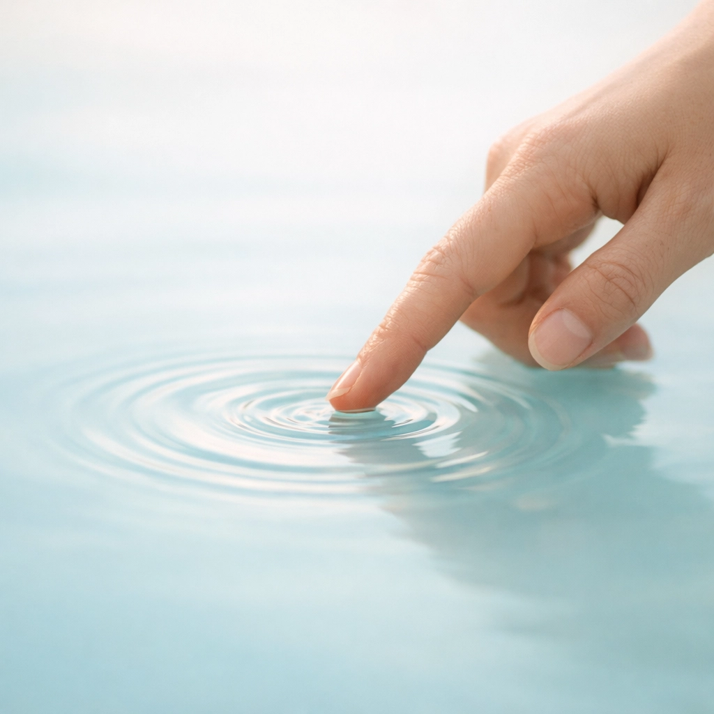 A hand touching water to create a ripple, emphasizing human connection and personal well-being.