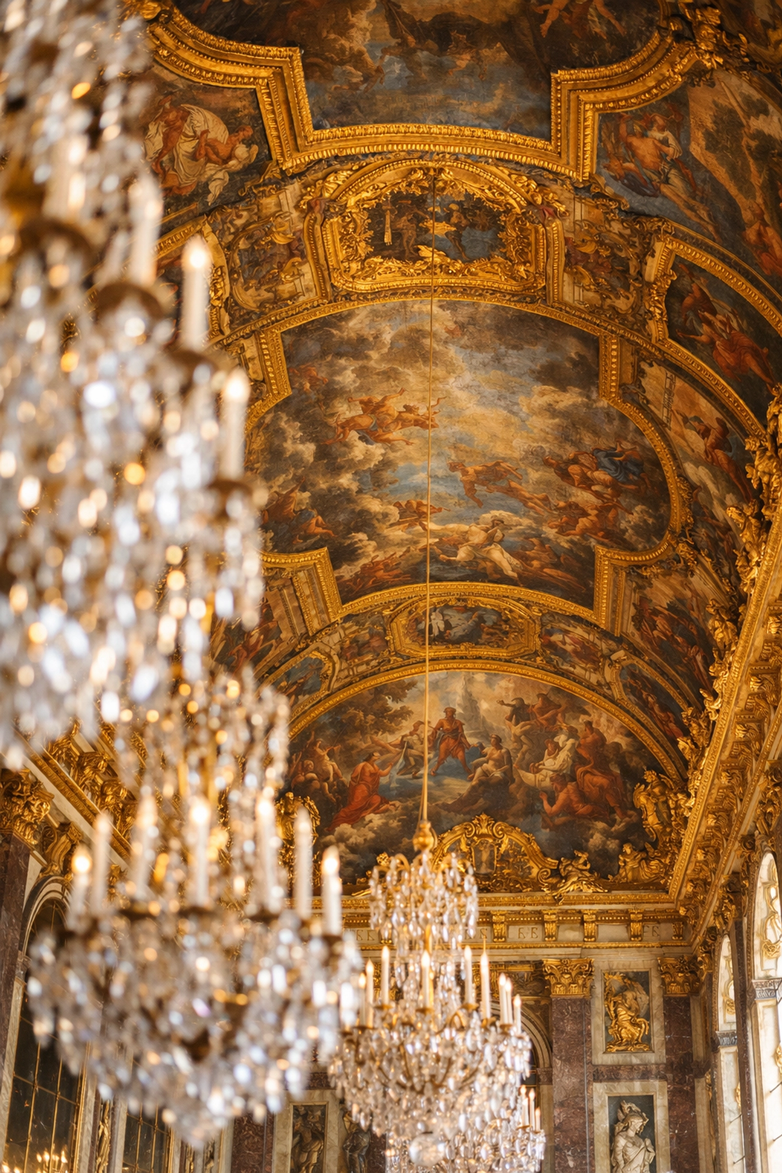 Detailed ceiling frescoes and gold moldings in the Hall of Mirrors at Versailles, a top photo spot.