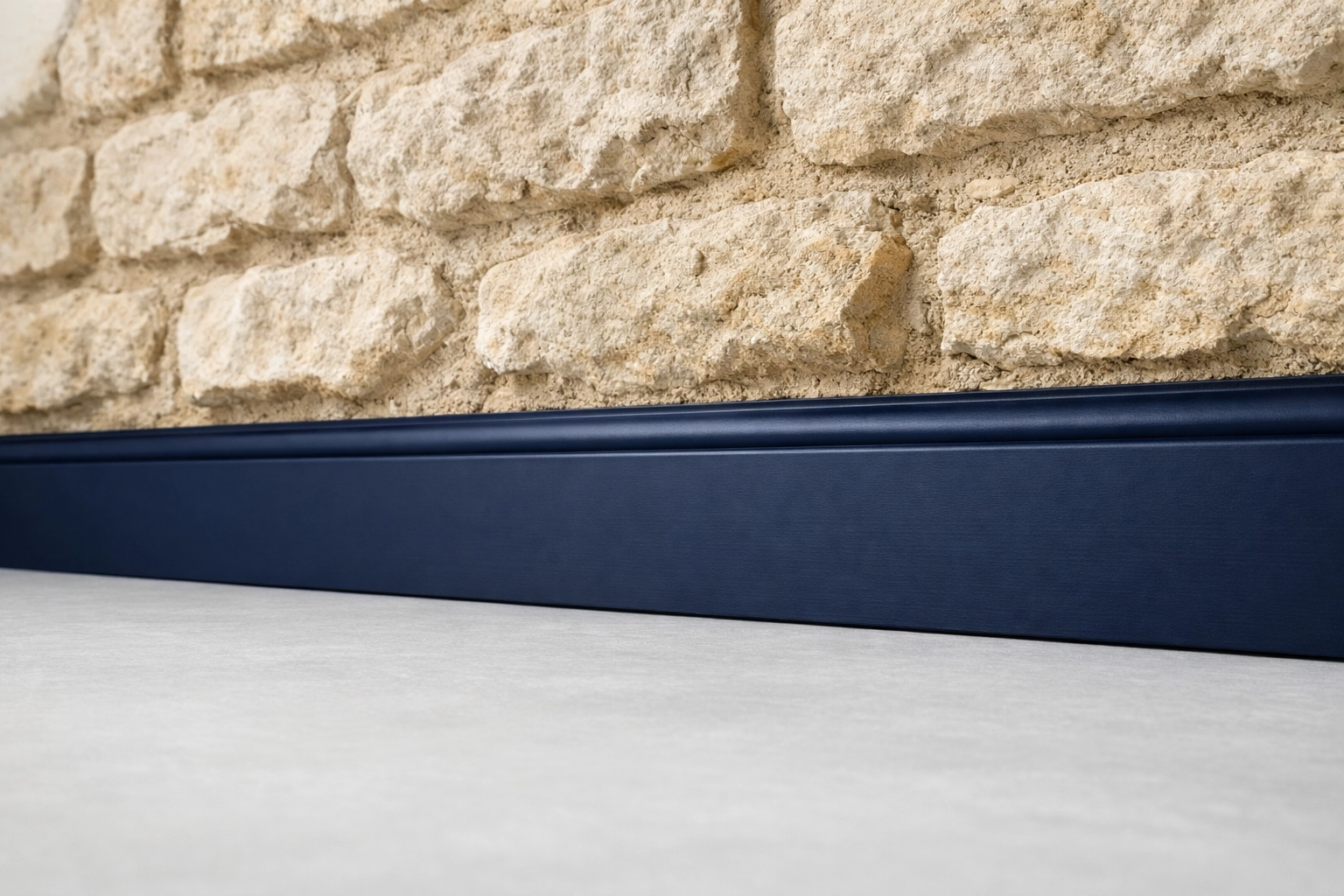 Navy blue skirting board detail against a traditional Gloucestershire Cotswold stone wall.