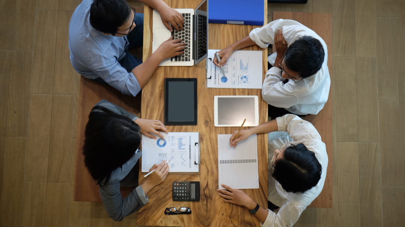 Four team members collaborating around a wooden table