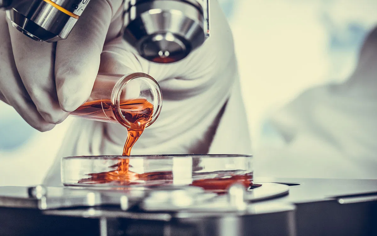 A precision-controlled laboratory setting showing the blending of amber-colored nutraceutical oils, signifying technical mastery in supplement formulation.