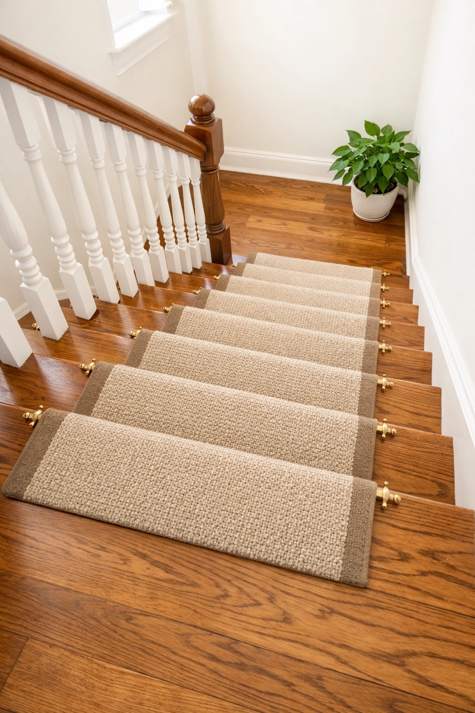 A secure beige carpet runner on hardwood stairs providing slip-resistant traction for safety.