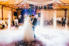 A newlywed couple shares their first dance surrounded by dramatic special FX and elegant uplighting