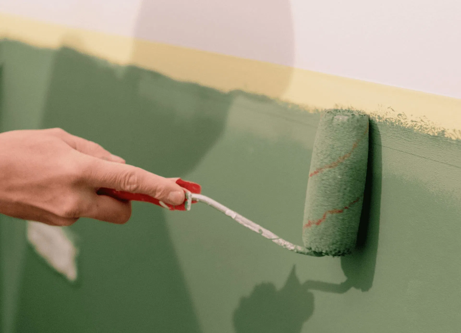painter-hand-roller-green-paint-yellow-accent-wall.webp