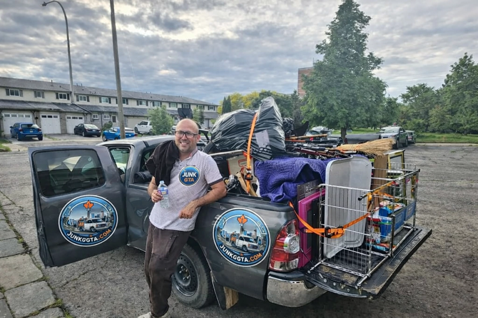 Roman, owner of Junk GTA, standing by his 2014 Toyota Tacoma loaded with junk for removal in a residential neighborhood