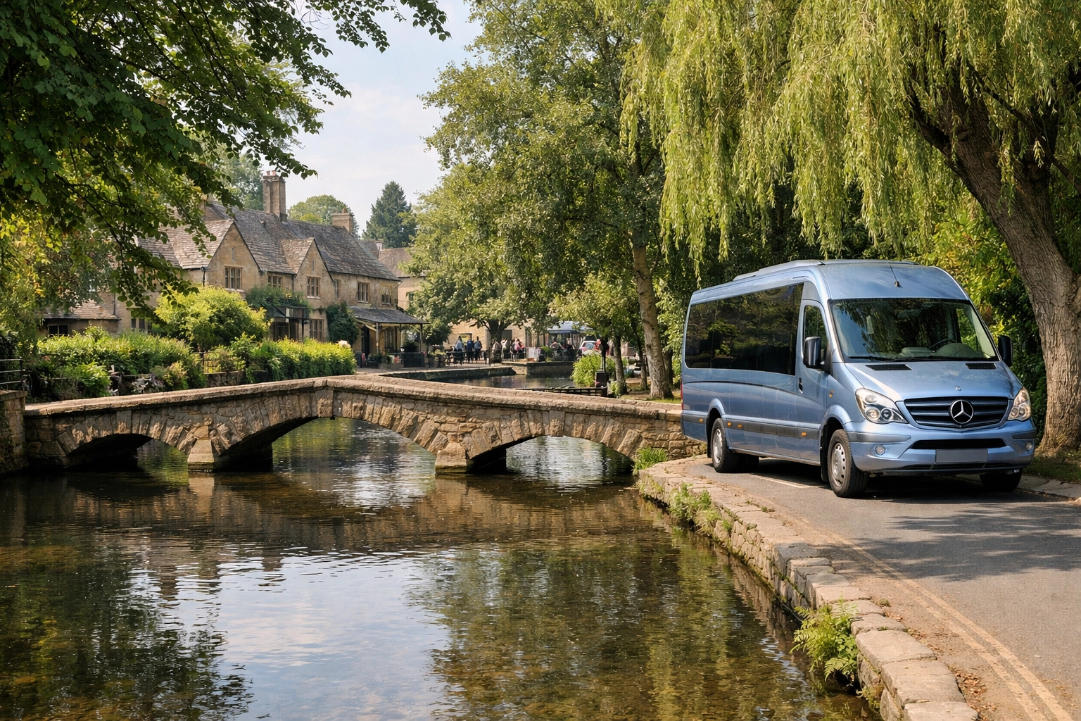 Scenic stone bridge over the River Windrush in Bourton-on-the-Water with a tour minibus nearby.
