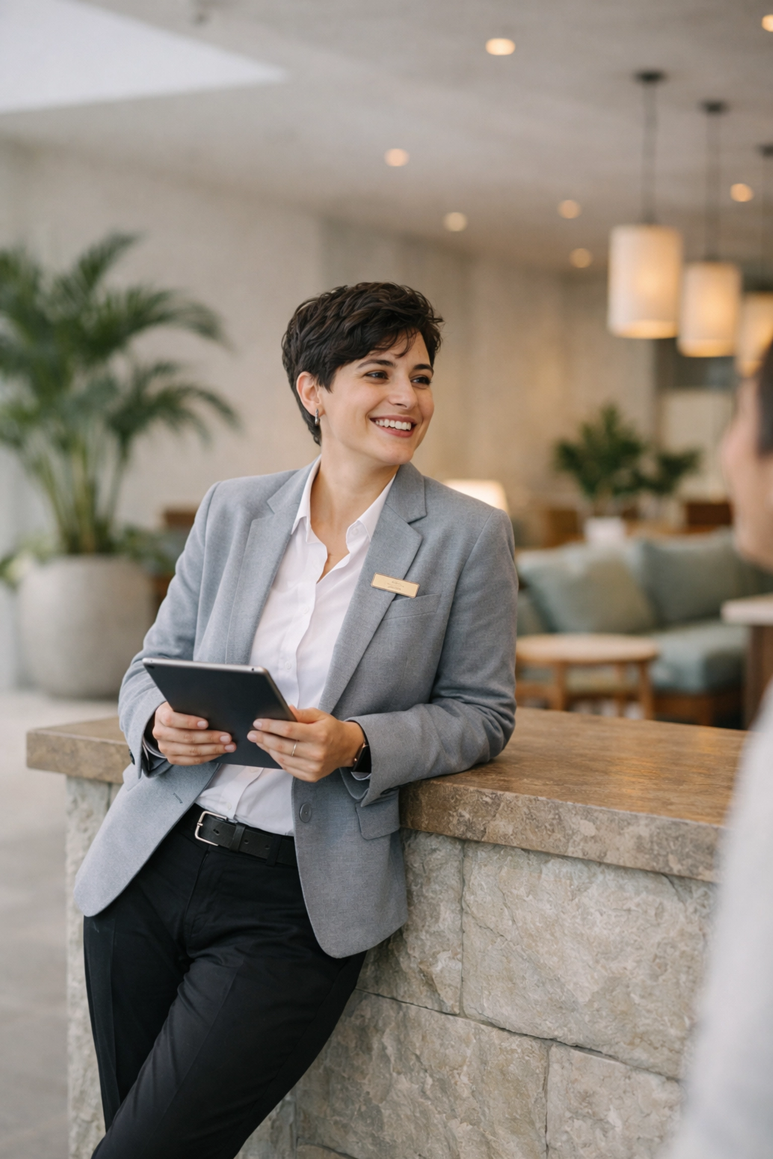 Hotel staff member using an easy-to-use hotel PMS on a tablet in a modern, open-concept lobby.
