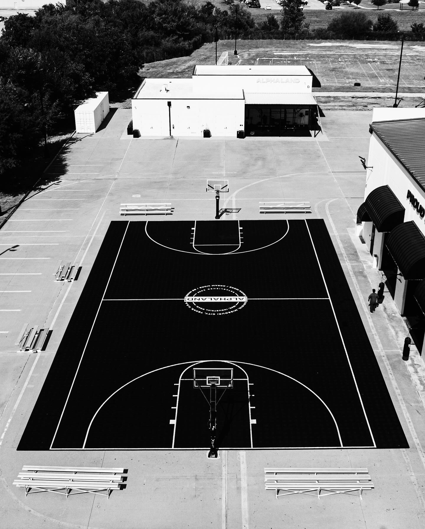 A newly constructed outdoor basketball court with clear, professional striping and custom branding