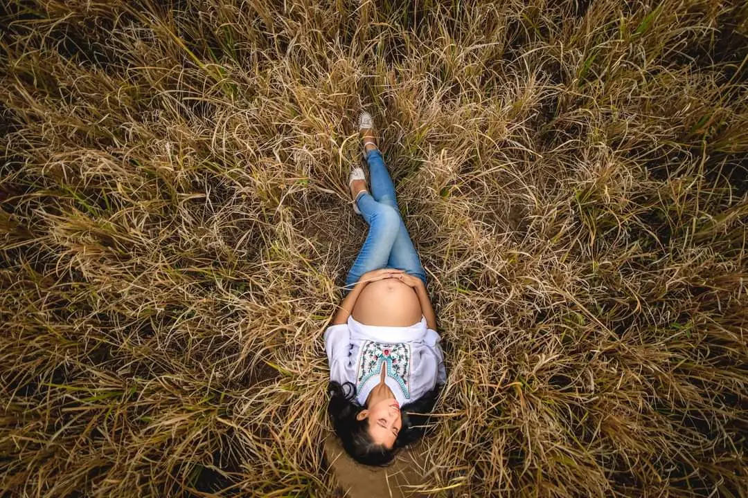 Aura embarazada en el campo, conectando con su cuerpo y su bebé desde una maternidad consciente.