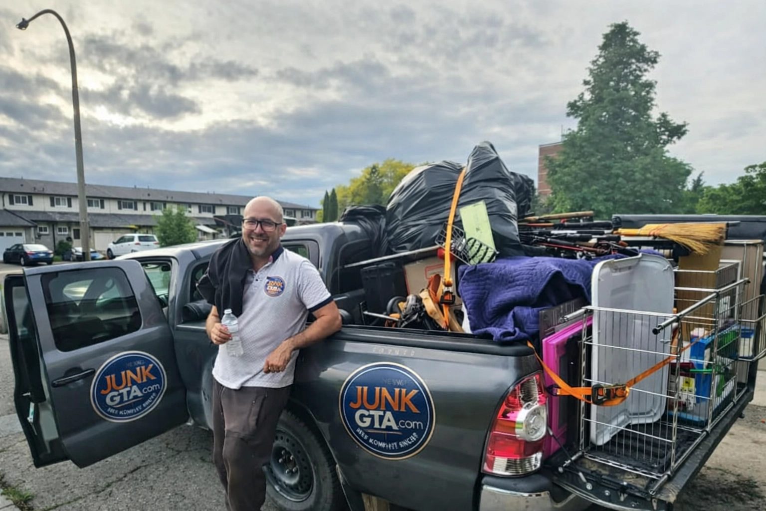 A Junk GTA crew member stands beside a truck loaded with various junk items prepared for responsible disposal