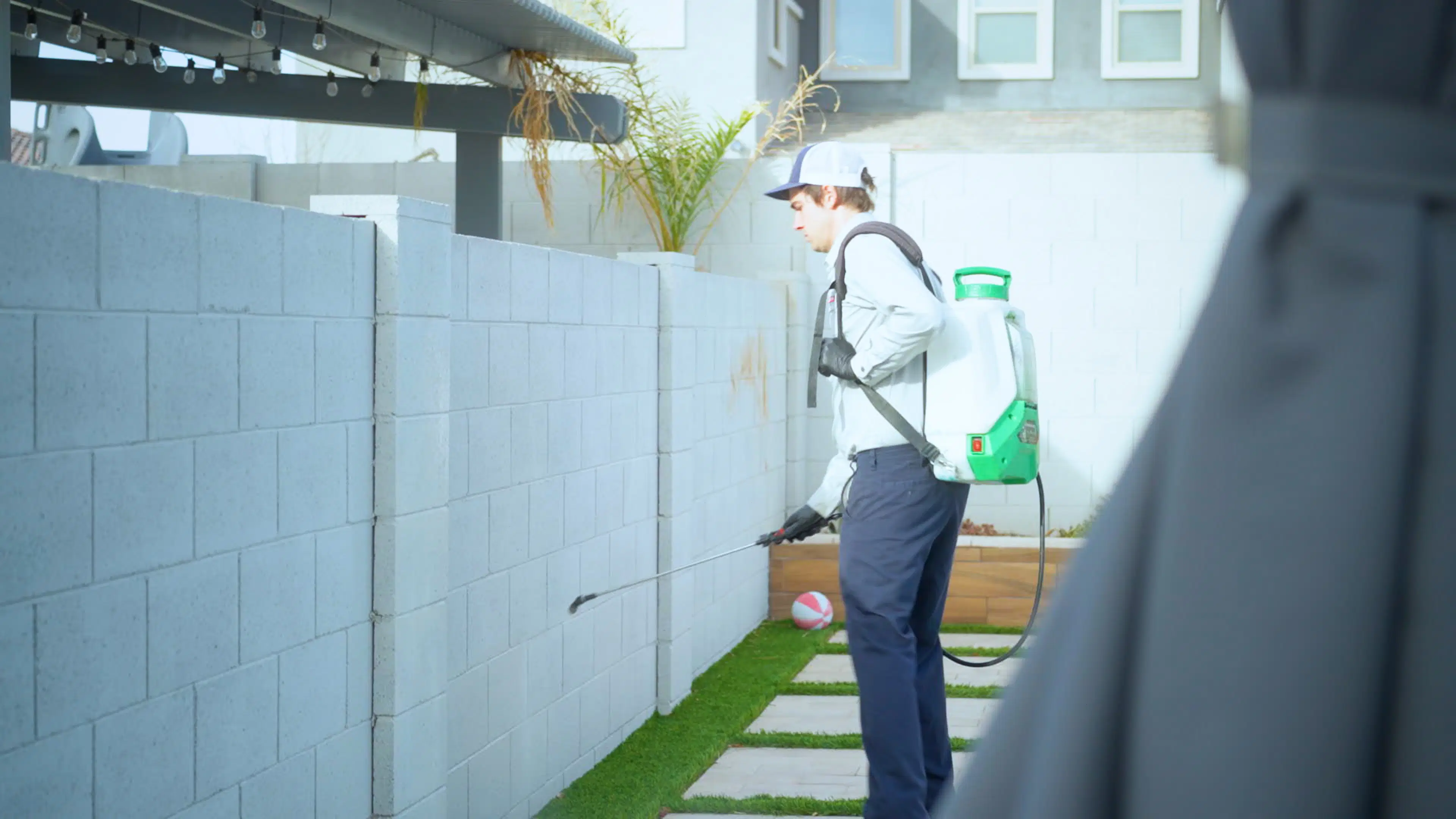 A Bucksworth technician performs targeted pest control treatment along a backyard block wall