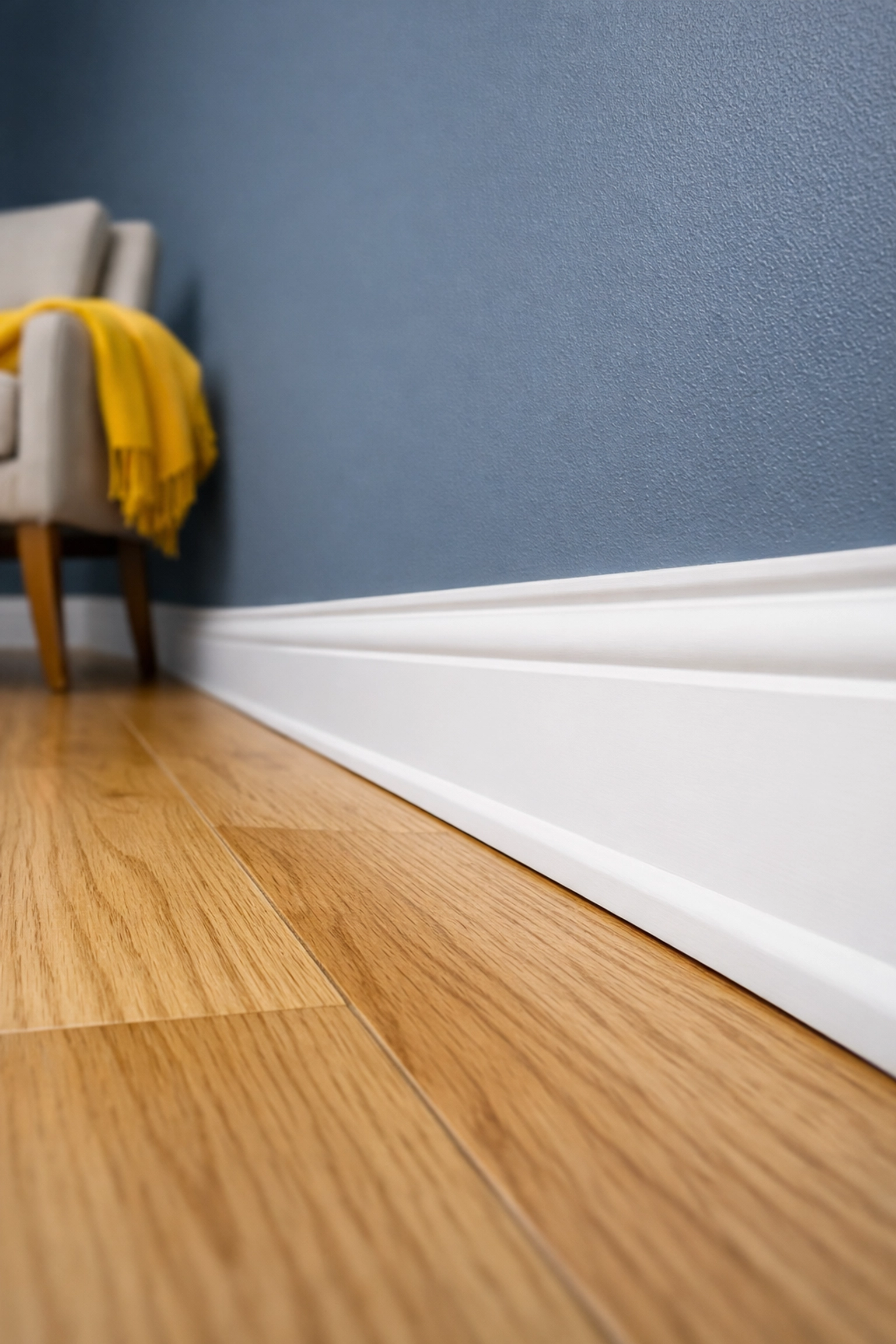 Close-up of dust-free white baseboards and clean hardwood floors in a Stow, MA residential home.