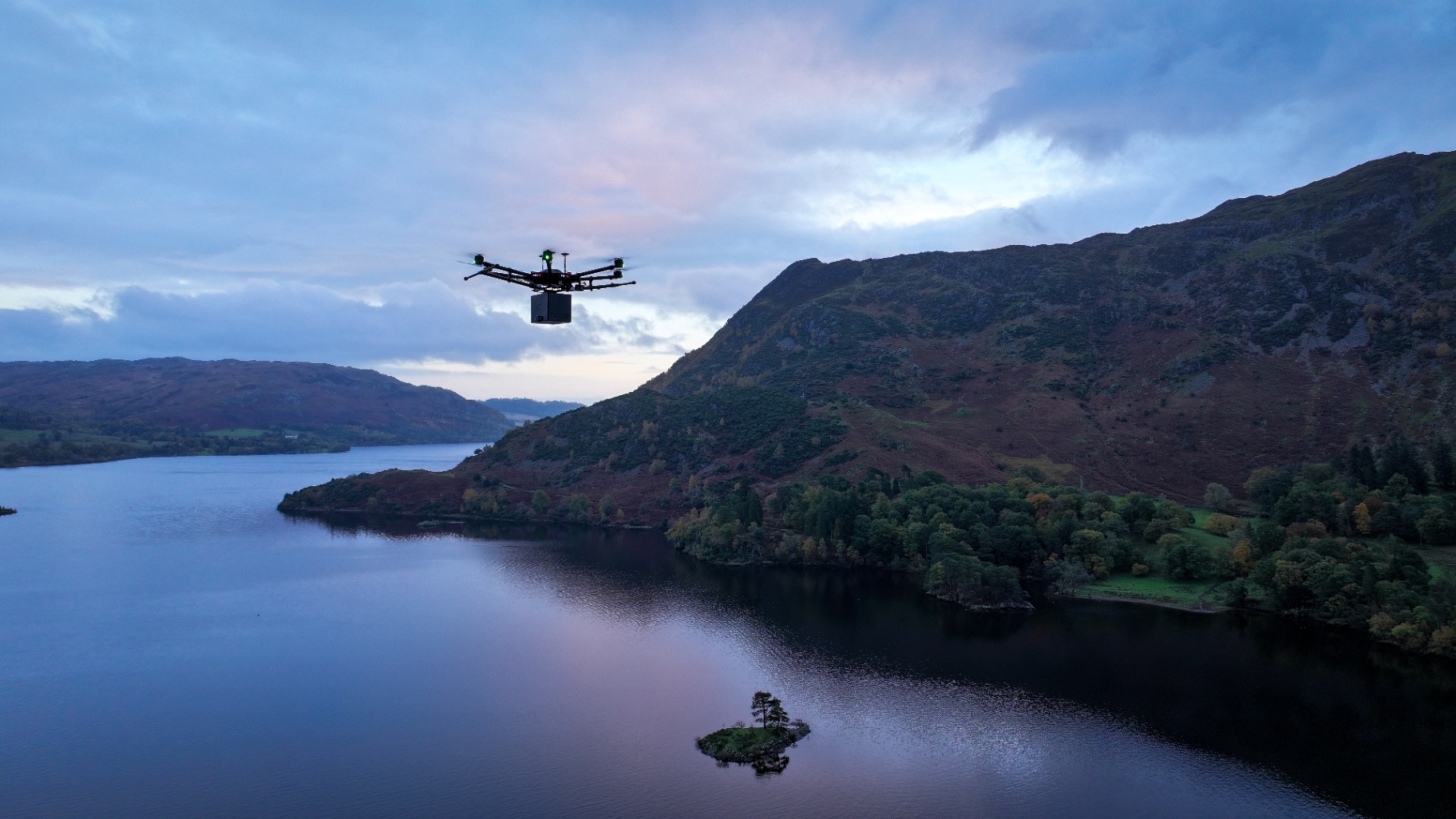 A drone equipped for ash scattering flies over a tranquil lake at dusk, showcasing a serene method of honouring loved ones.
