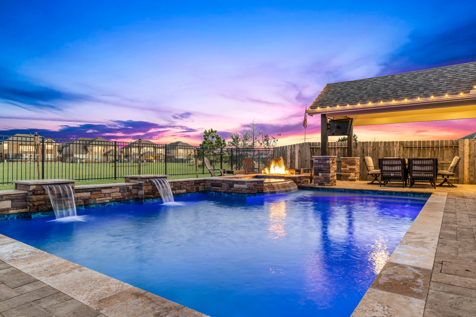 Luxury backyard pool with integrated water features and lighting at dusk