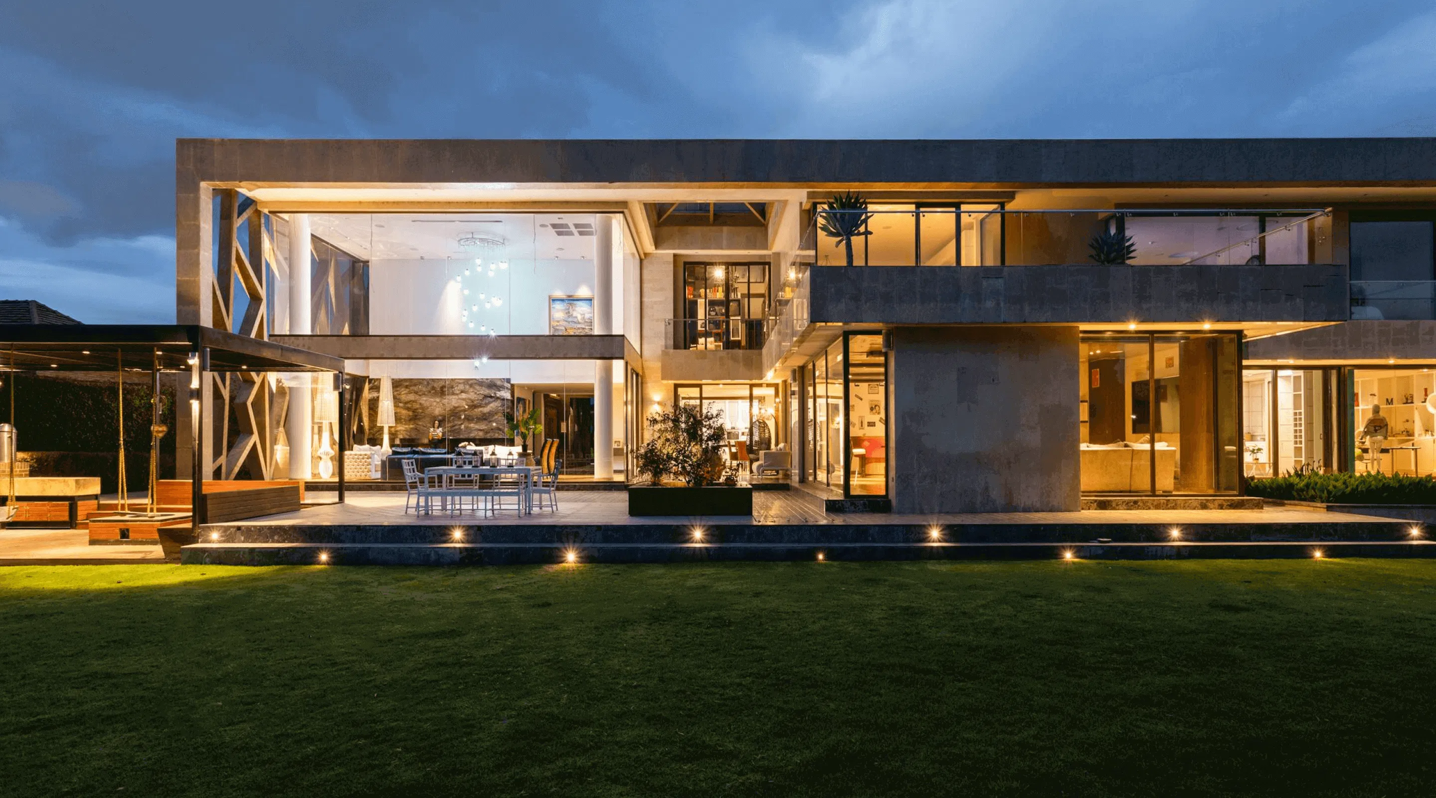 Modern two-story luxury home with extensive glass walls and illuminated exterior