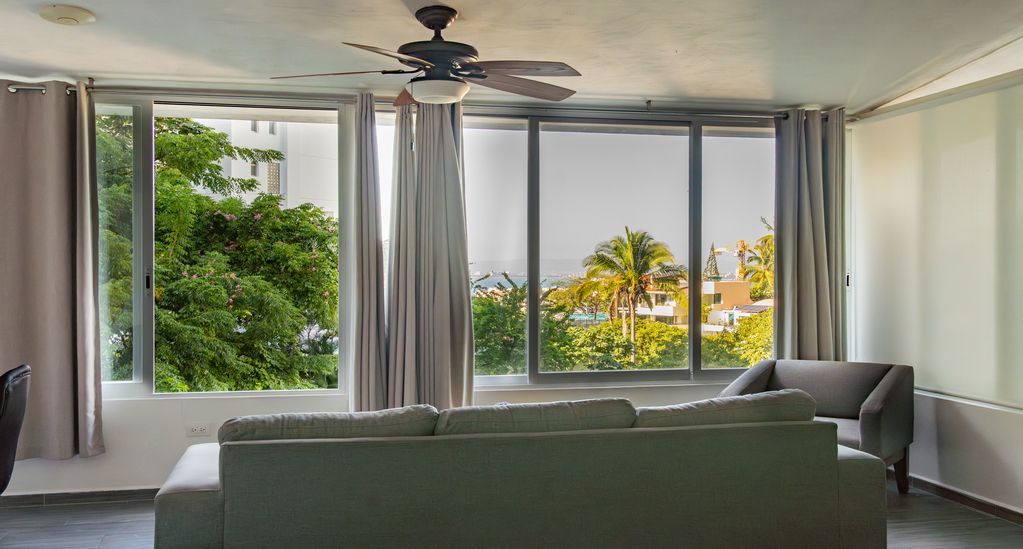 Spacious condo living room in Puerto Vallarta with large windows and panoramic views of greenery