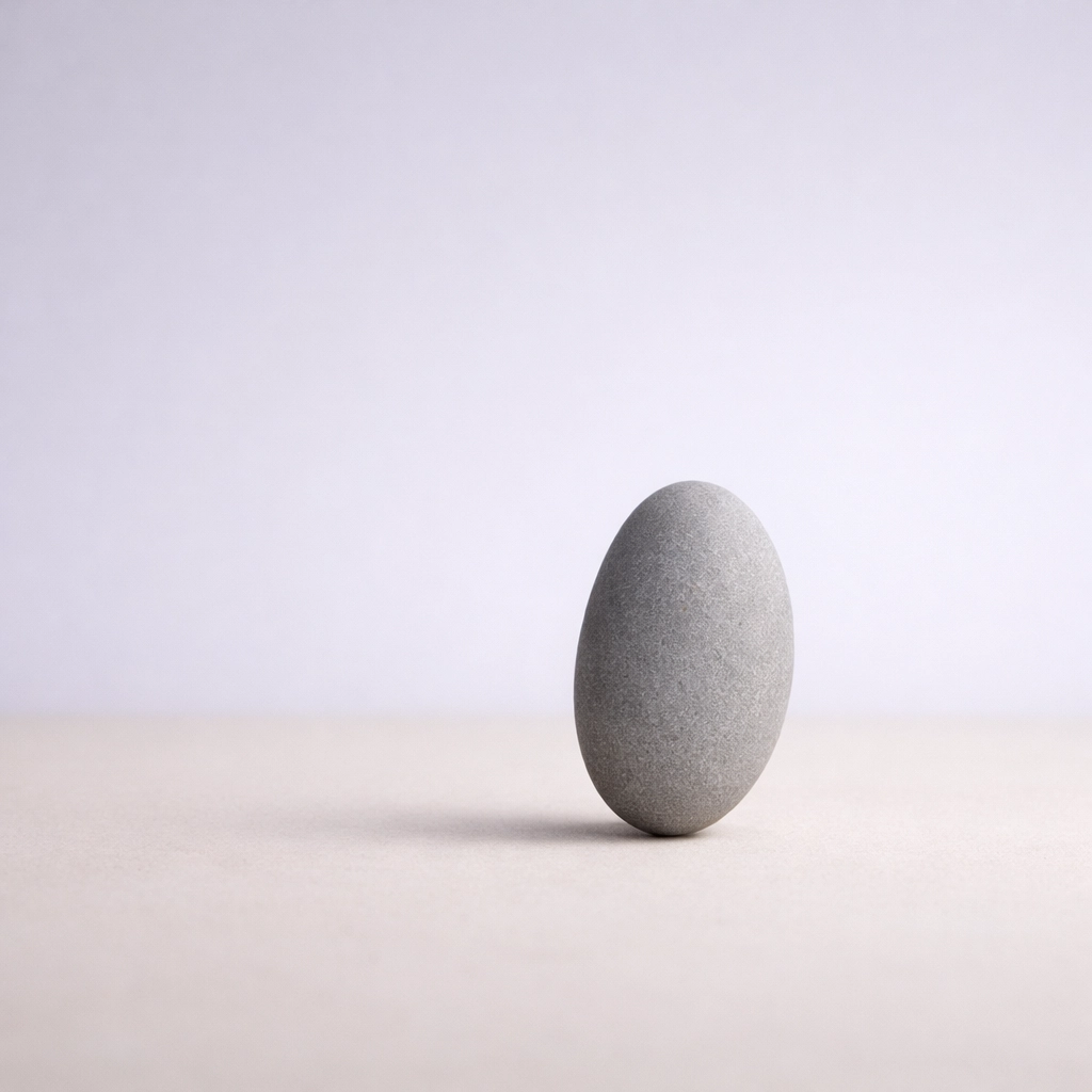 A balanced river stone on a soft background symbolizing the fragile equilibrium of executive burnout recovery.