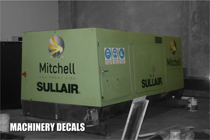 Close-up of worker pointing to bright safety decal on heavy machinery in an industrial setting