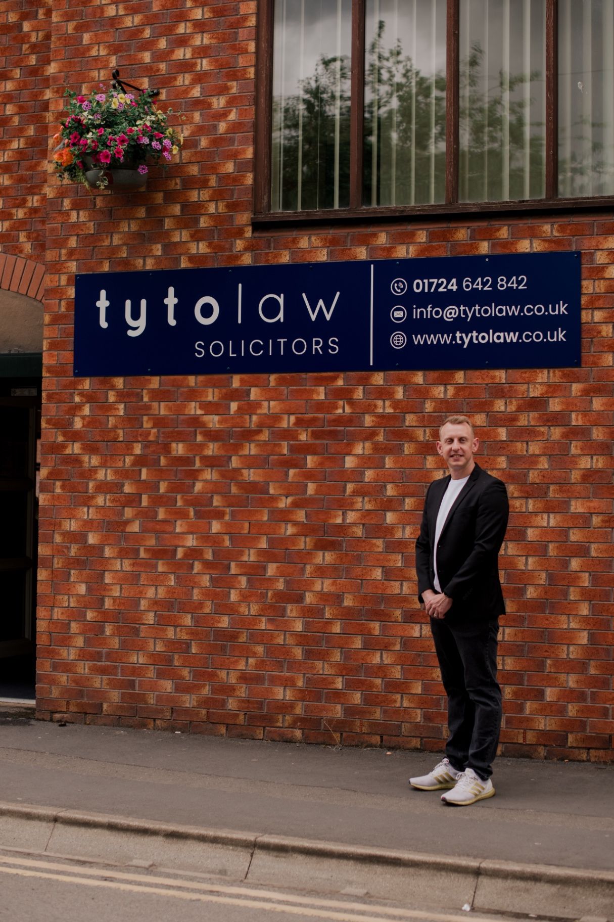 Oliver Saxon standing outside the Tyto Law office next to the company sign