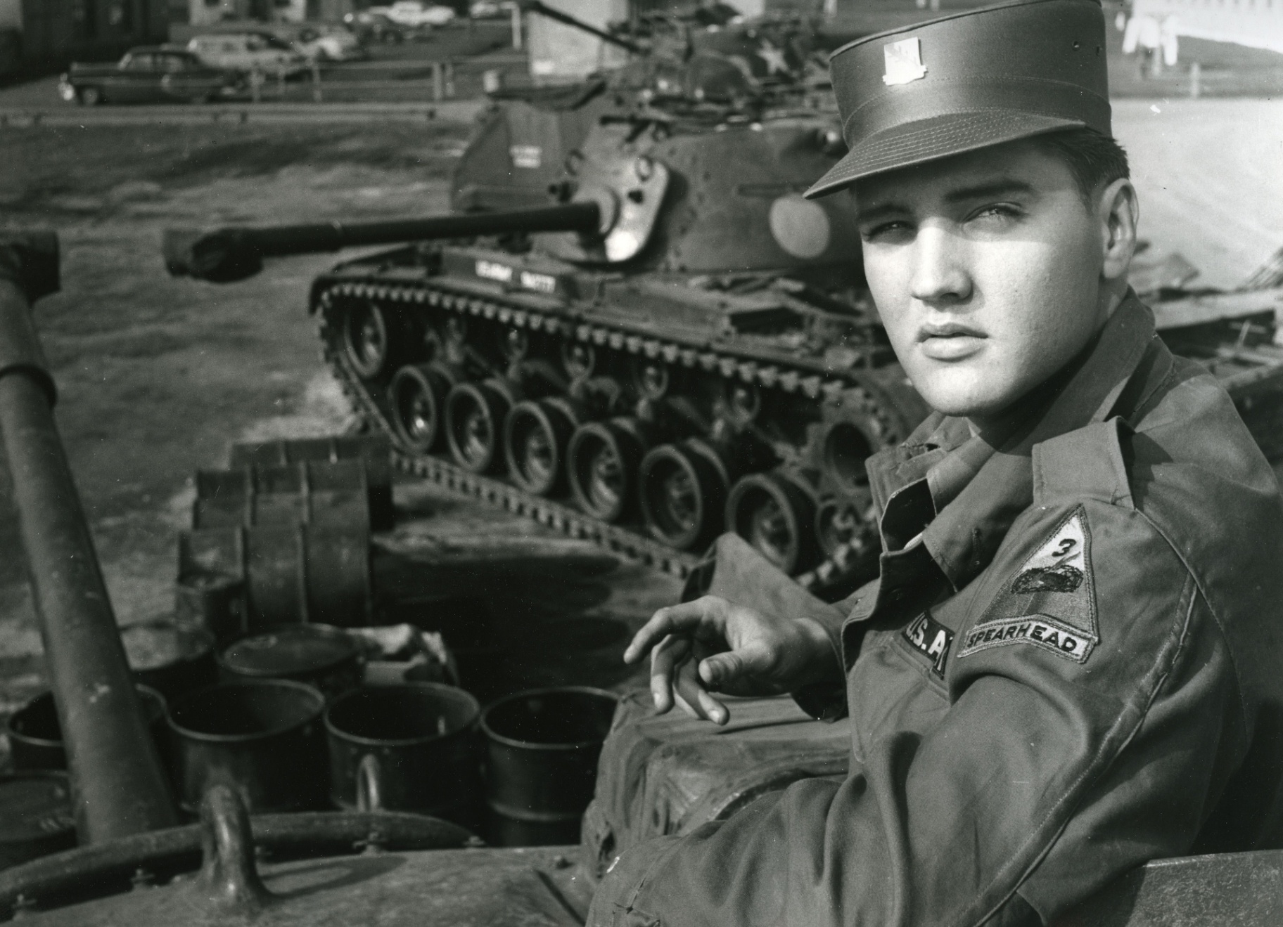 Elvis Presley in U.S. Army uniform seated on a tank