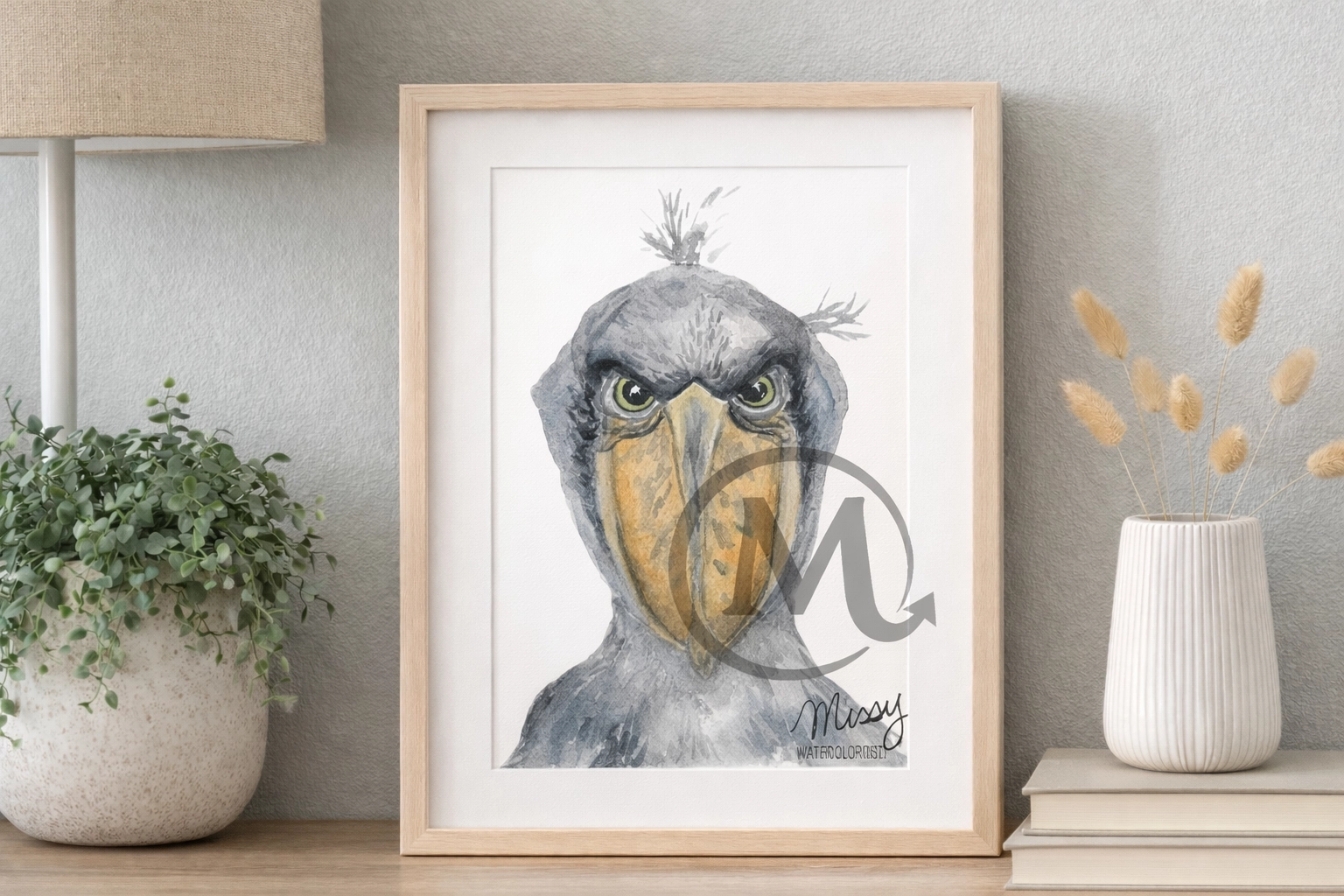 Missy’s original Shoebill watercolor displayed in a styled real-life frame mockup in a calm room setting, with the original watermark and signature fully visible.