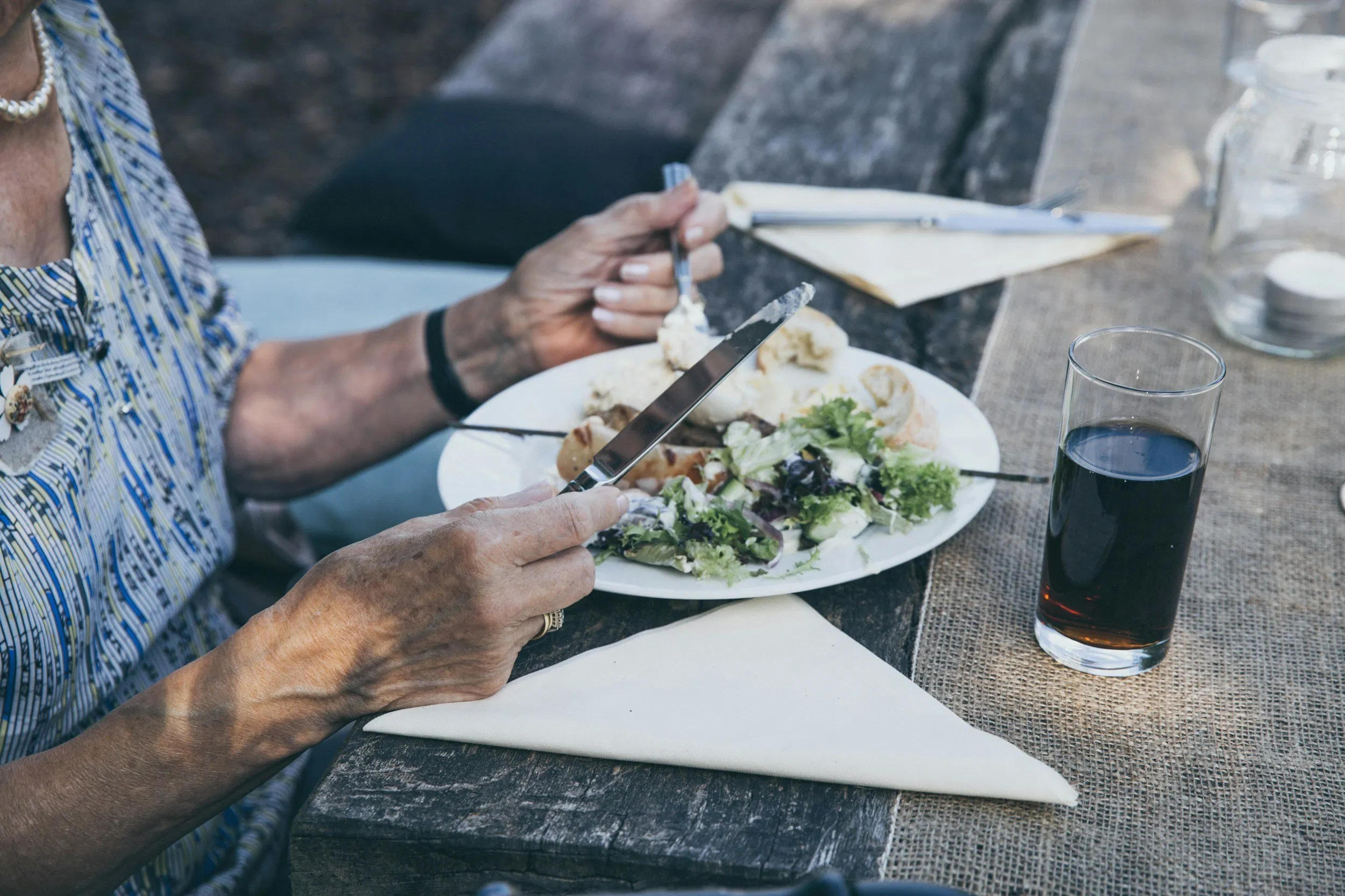 Senior enjoying a healthy meal outside at a wooden table