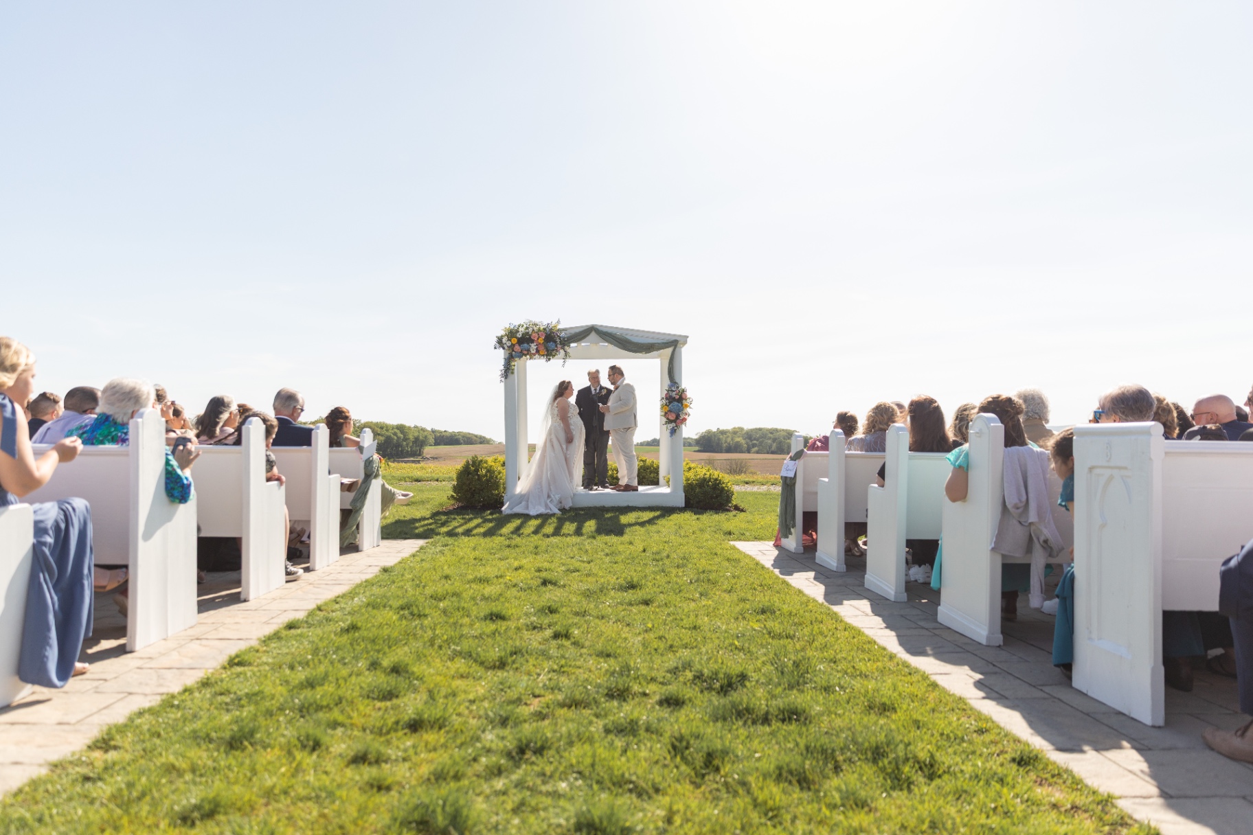 A candid, close kiss beneath the arbor—lush greenery framing their moment