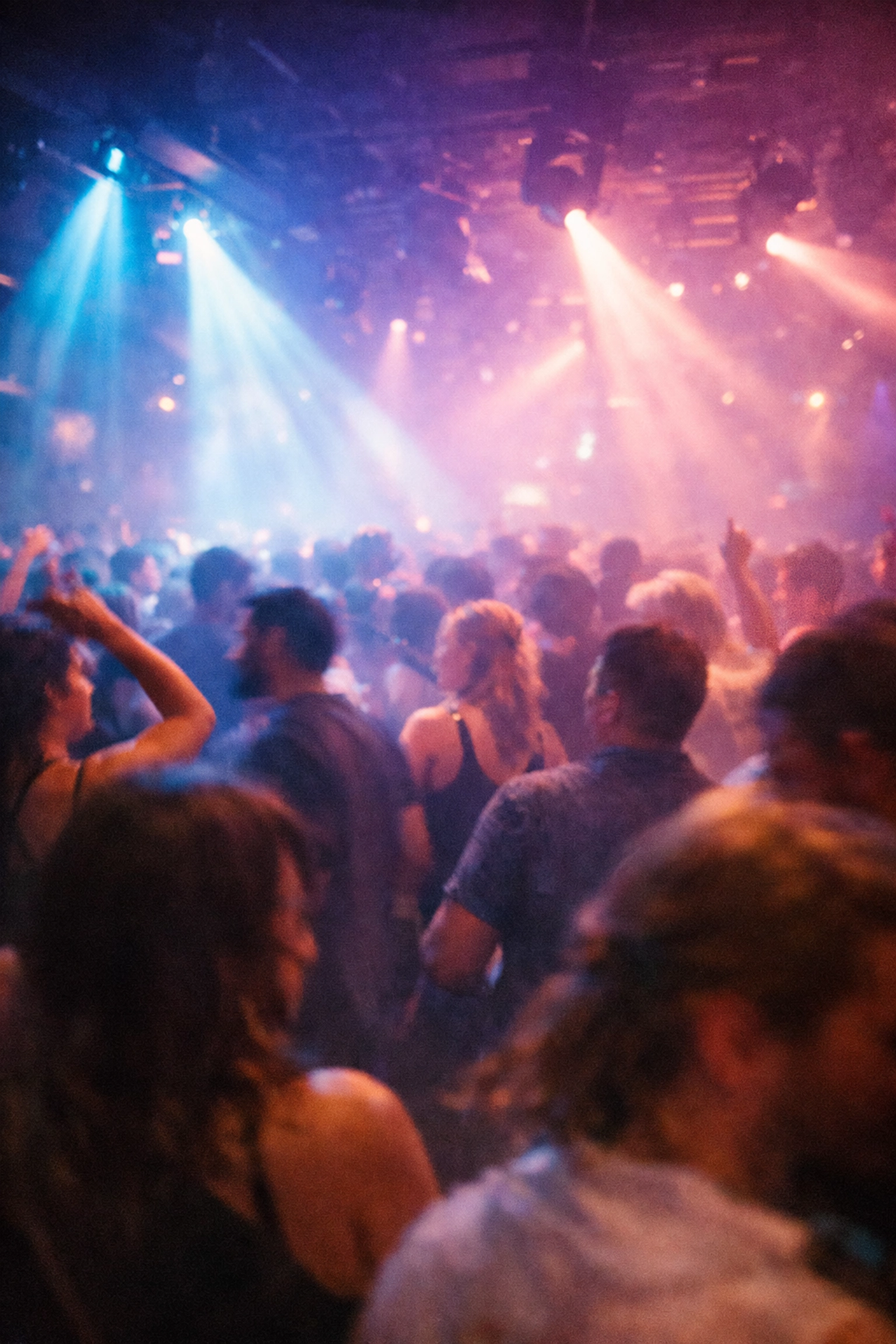 People dancing on a crowded Montreal dance floor under vibrant blue and violet club lights.