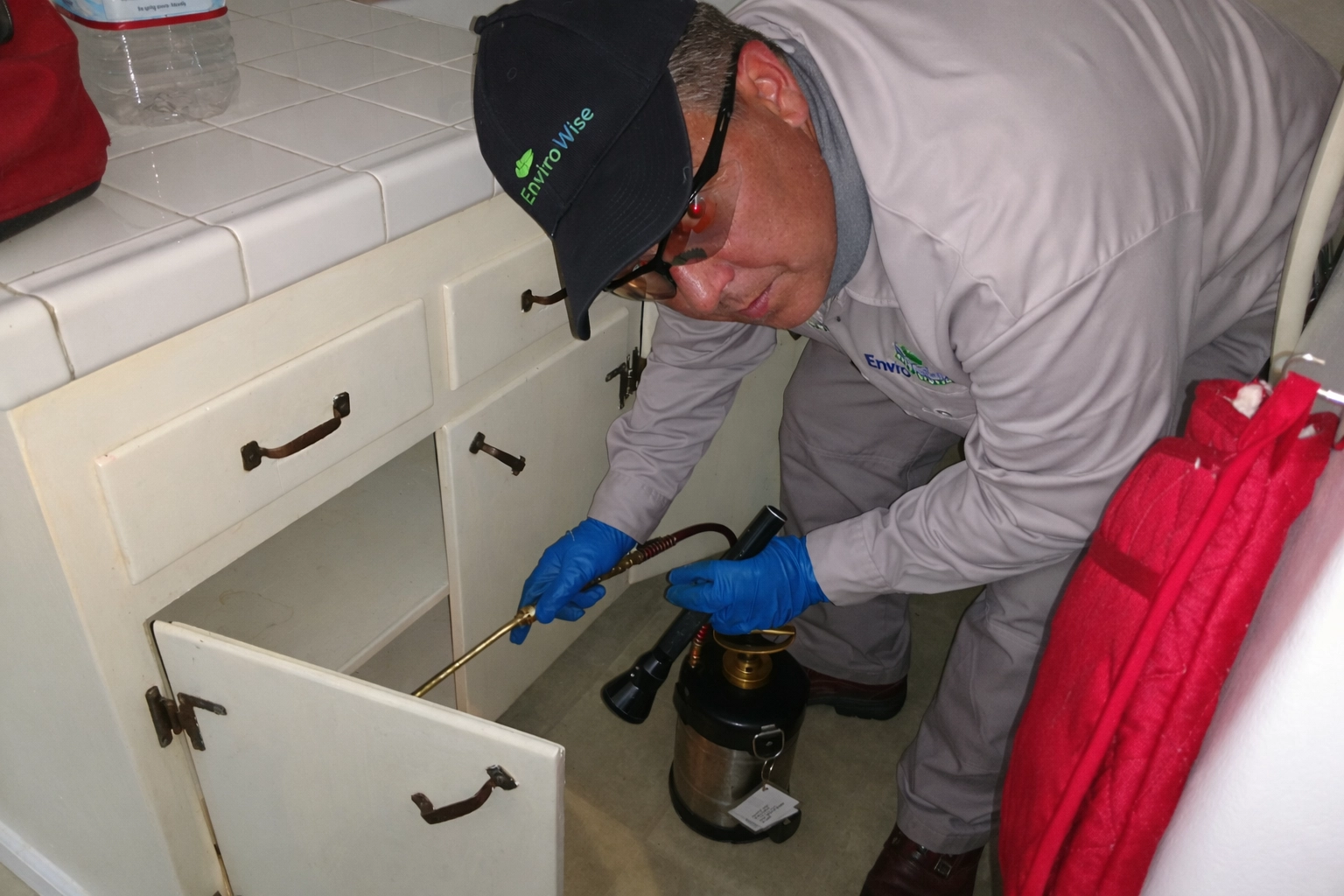 EnviroWise technician treating kitchen cabinet