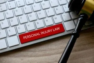 Close-up of a computer keyboard with a prominent red 'PERSONAL INJURY LAW' key and a judge’s gavel