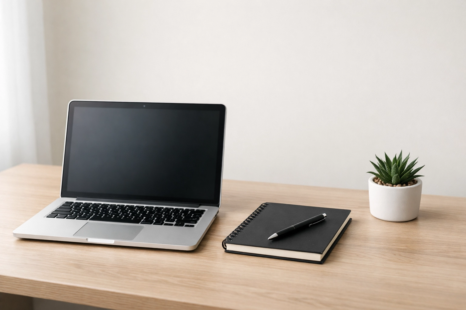 Modern office desk with a laptop and plant, symbolizing organized bookkeeping for small businesses.