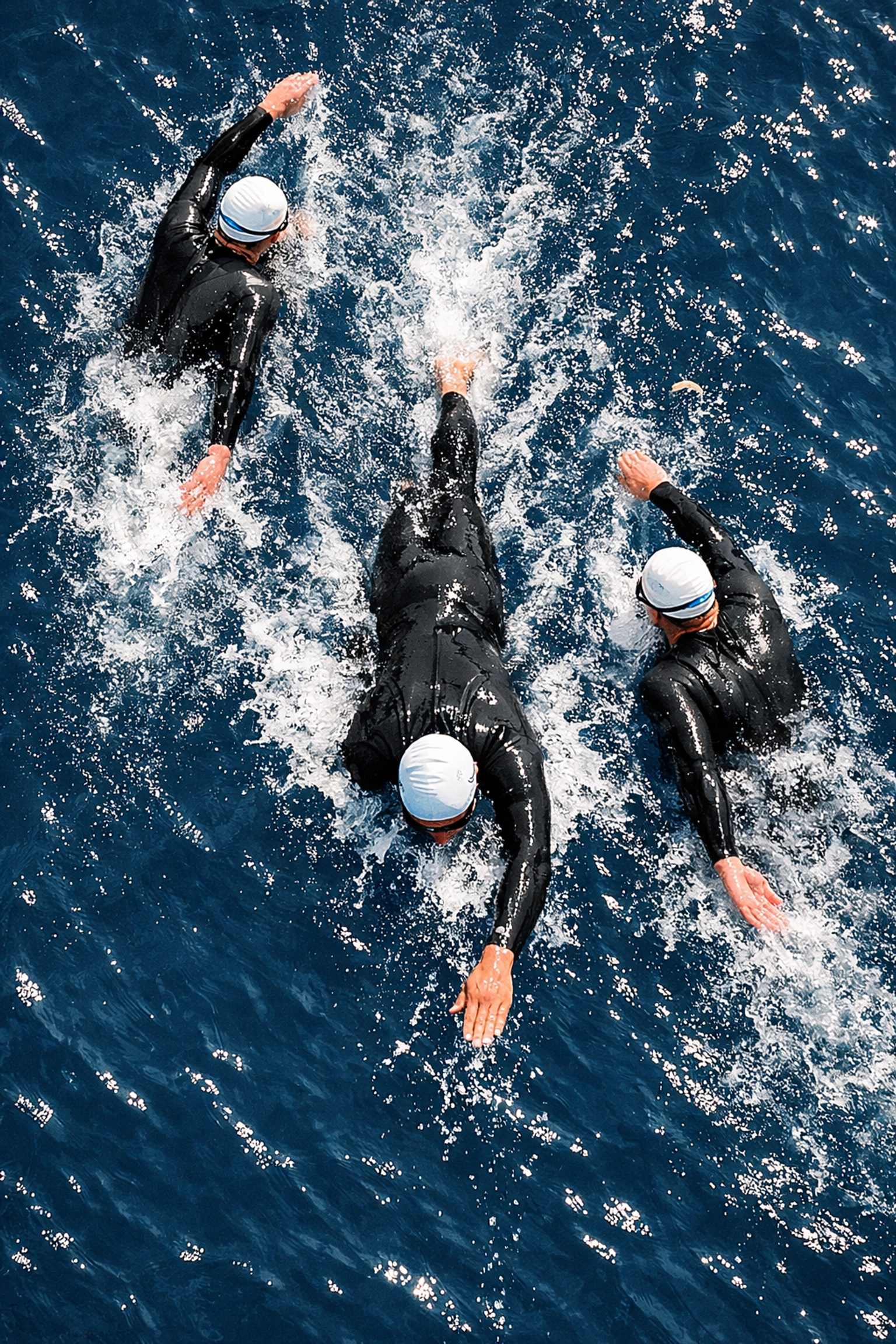 Tres triatletas en formación de drafting durante segmento de natación en aguas abiertas