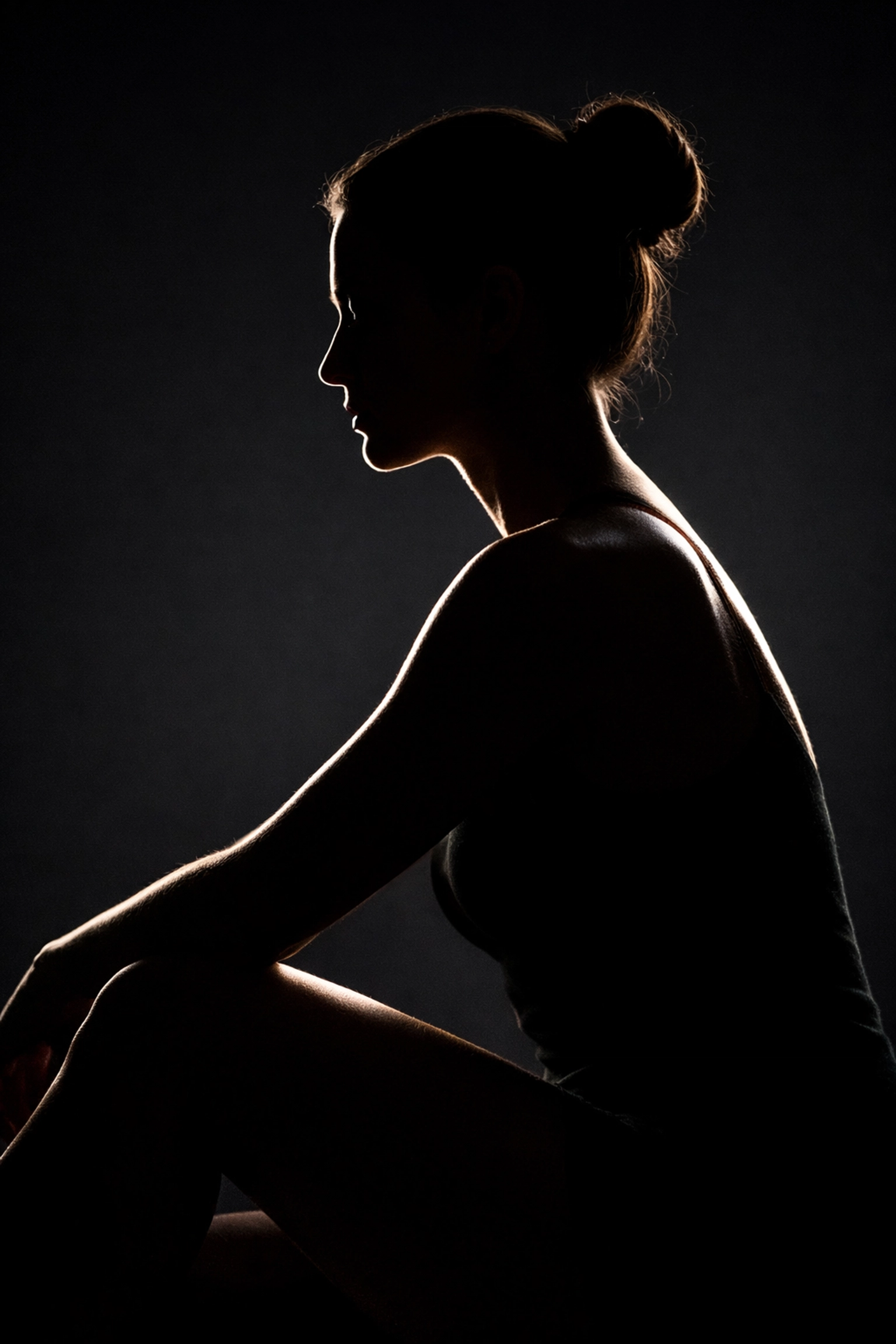 Subtle rim lighting silhouette highlighting the sculpted human form in a fine art nude photography setup.