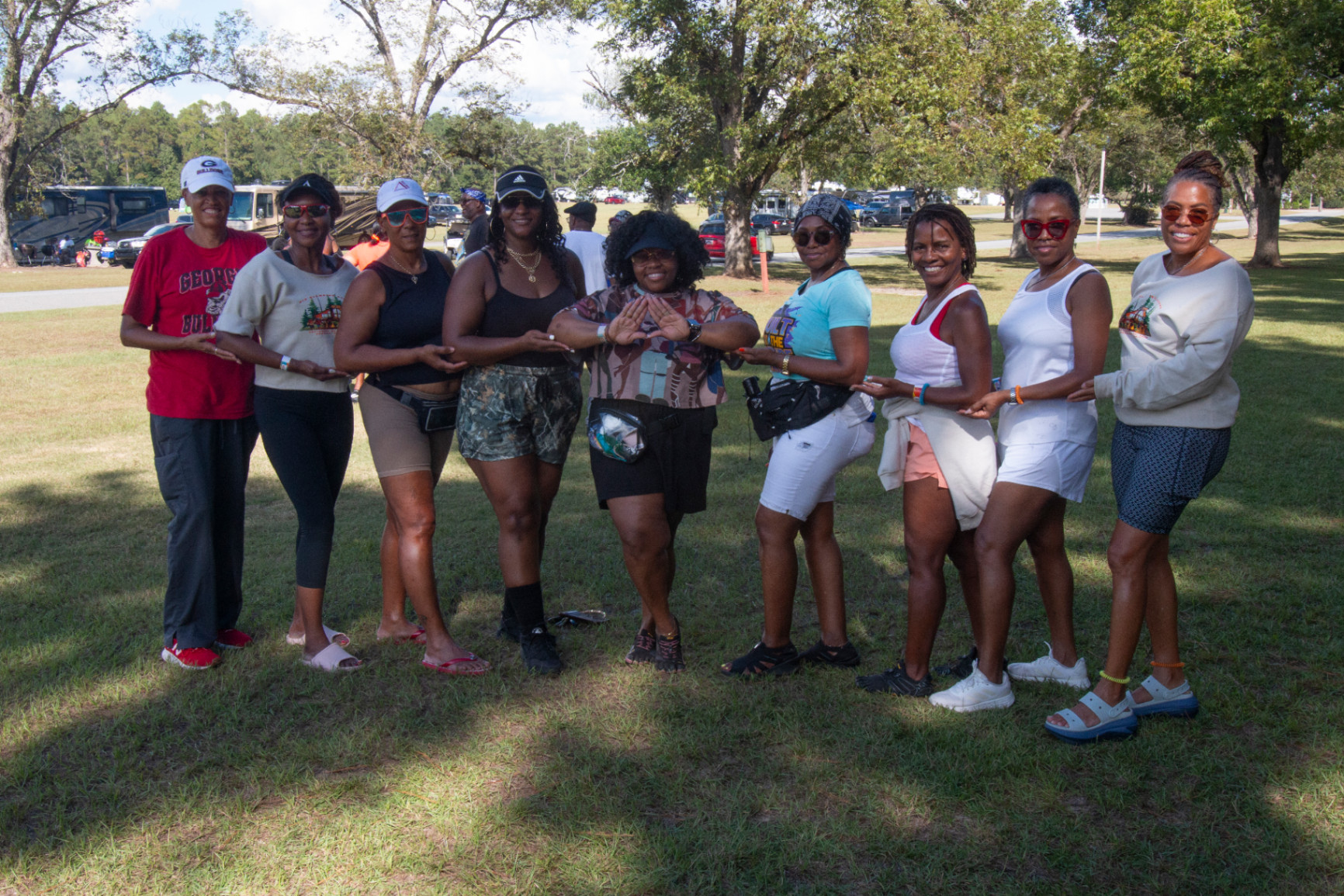 A group of women smiling and making hand signs, enjoying sisterhood at the campout