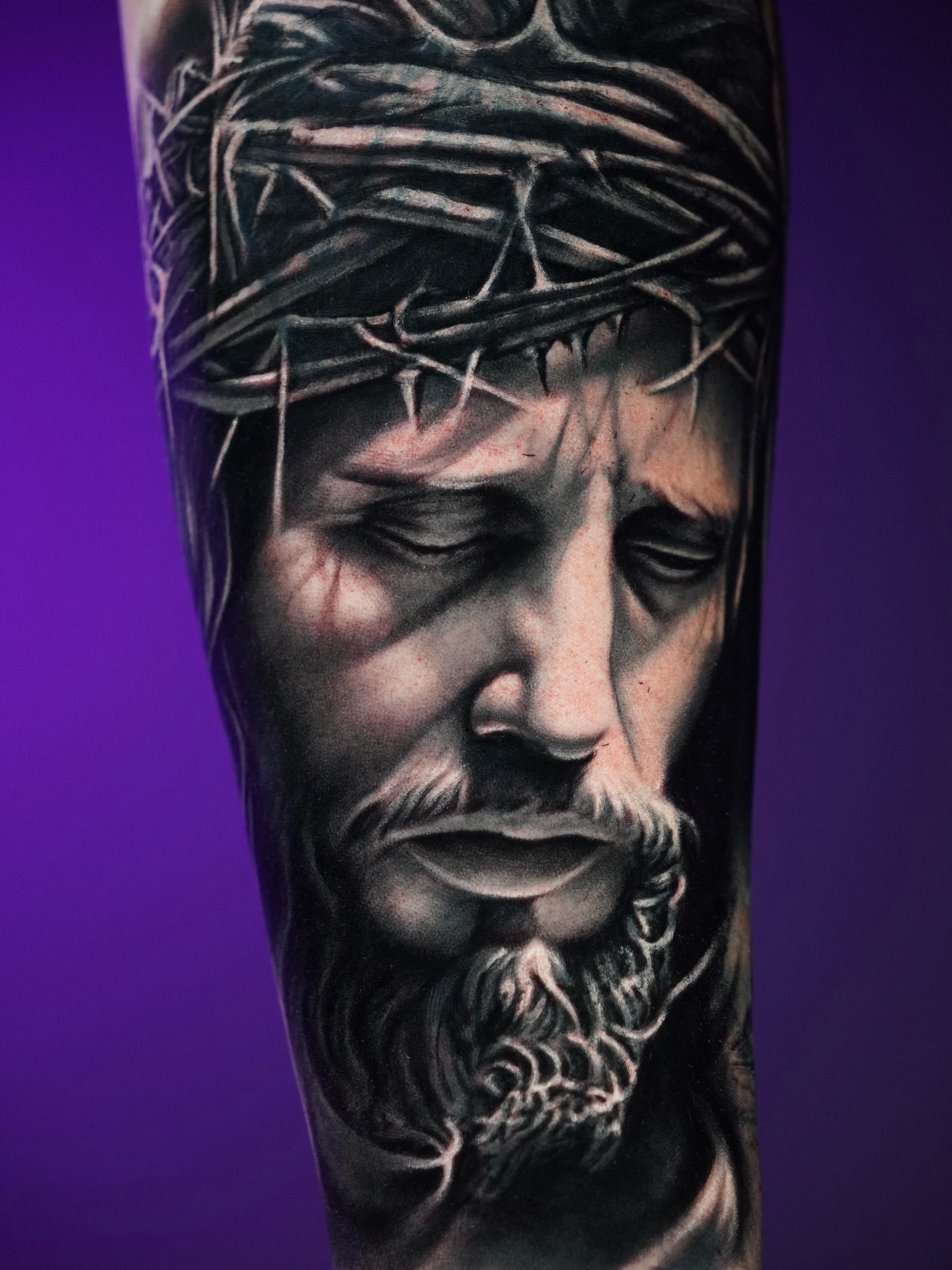 Black and grey realism tattoo of a man with a crown of thorns, showing detailed facial structure