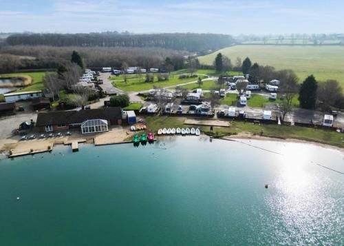 A serene lakeside caravan pitch in Leicestershire with a modern touring caravan parked on a hardstanding pitch overlooking a calm lake at sunset