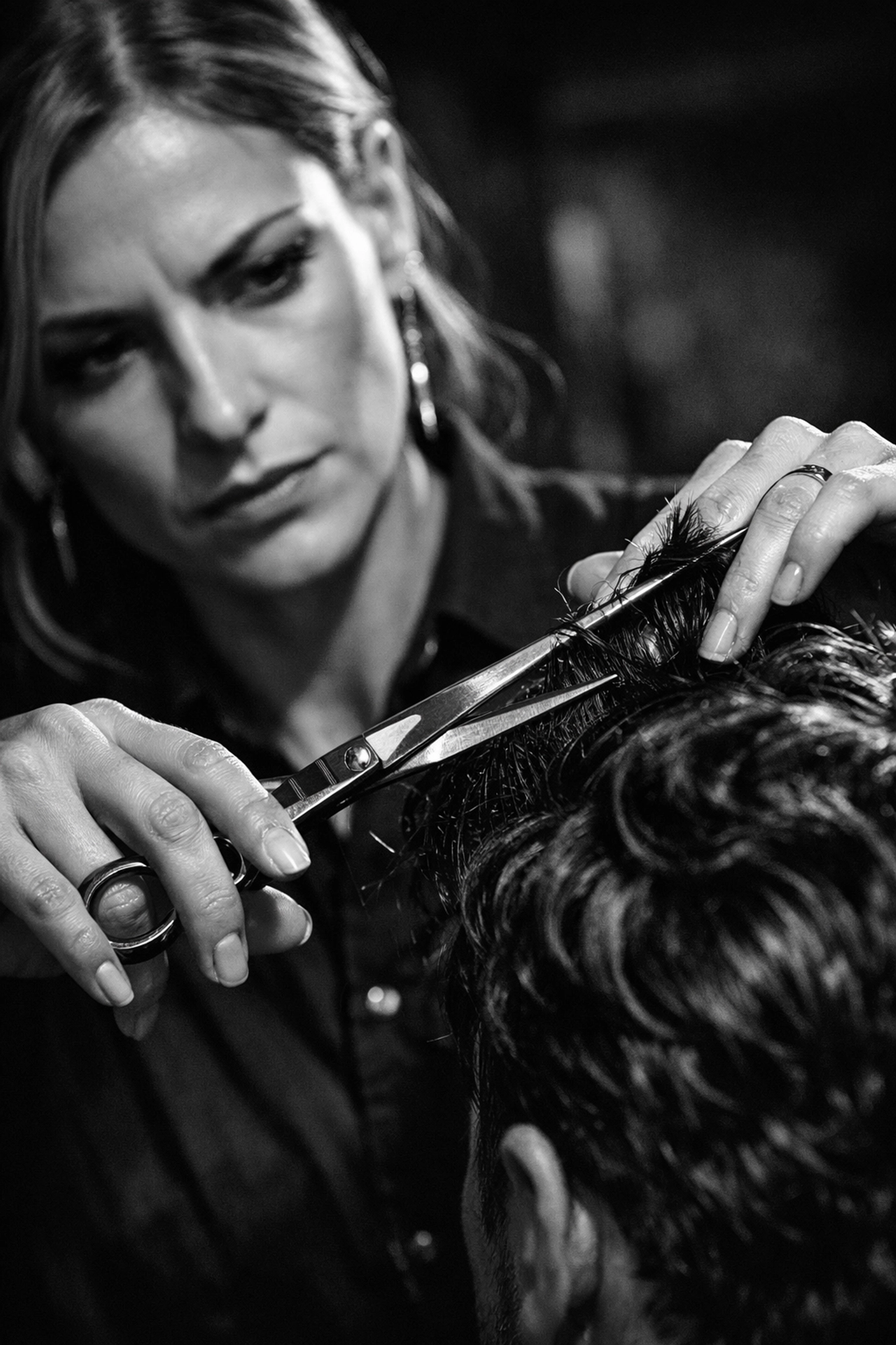 Female barber performing a precision haircut on wavy hair at X-Quisite Cutz school.