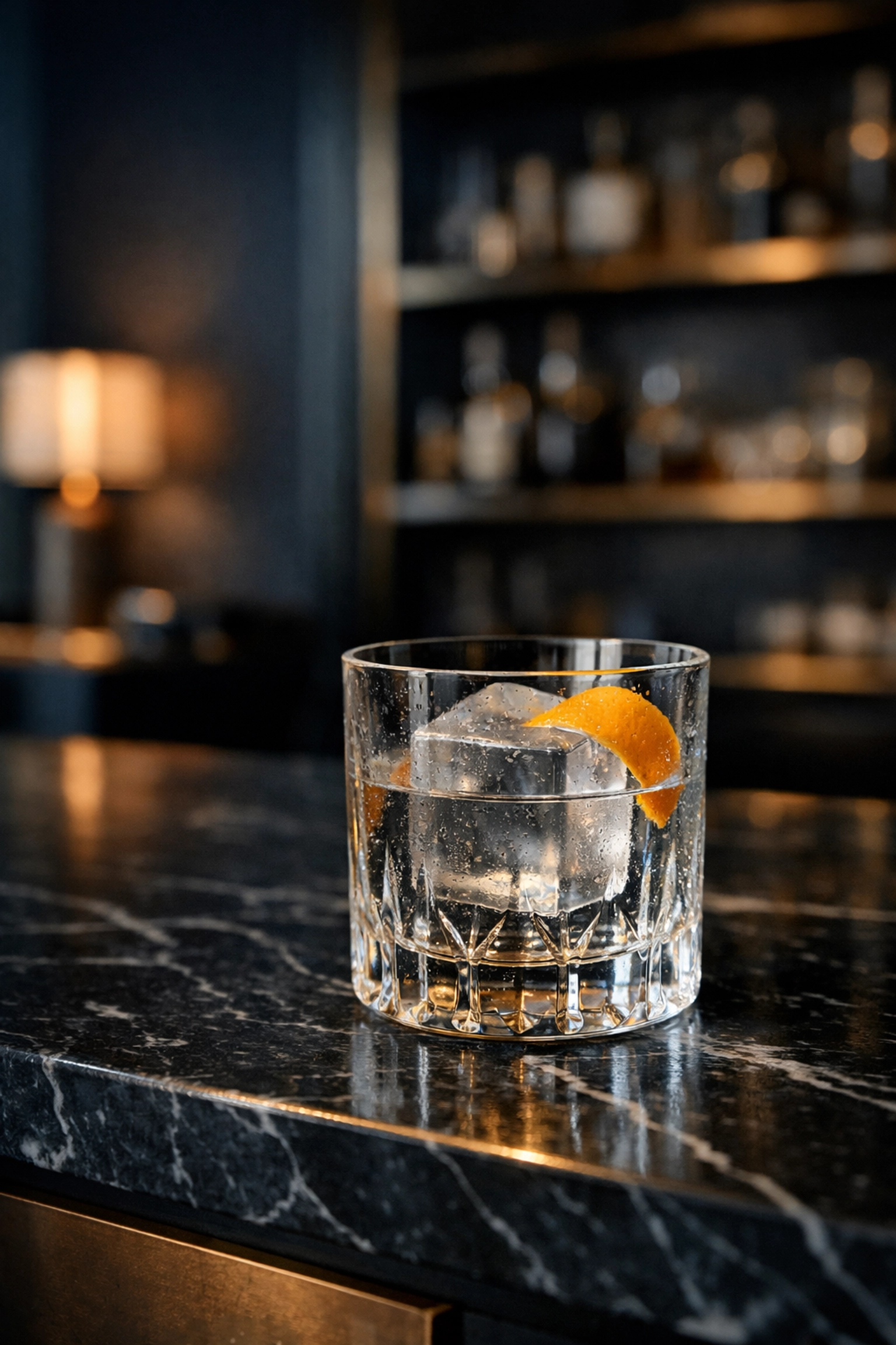 A crystal glass on a black marble hotel bar representing refined and personalized guest service.