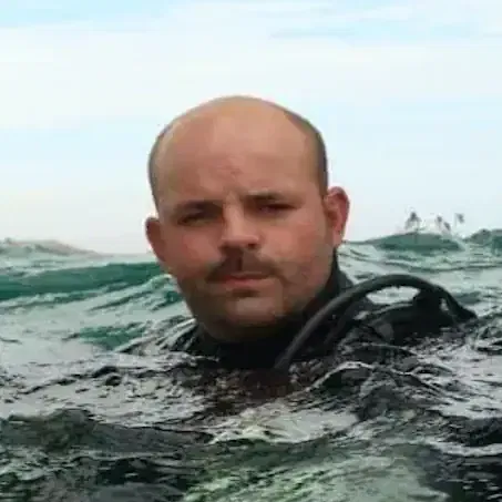 A focused man surfacing from deep water, representing resilience and the moment of rising above disruption.