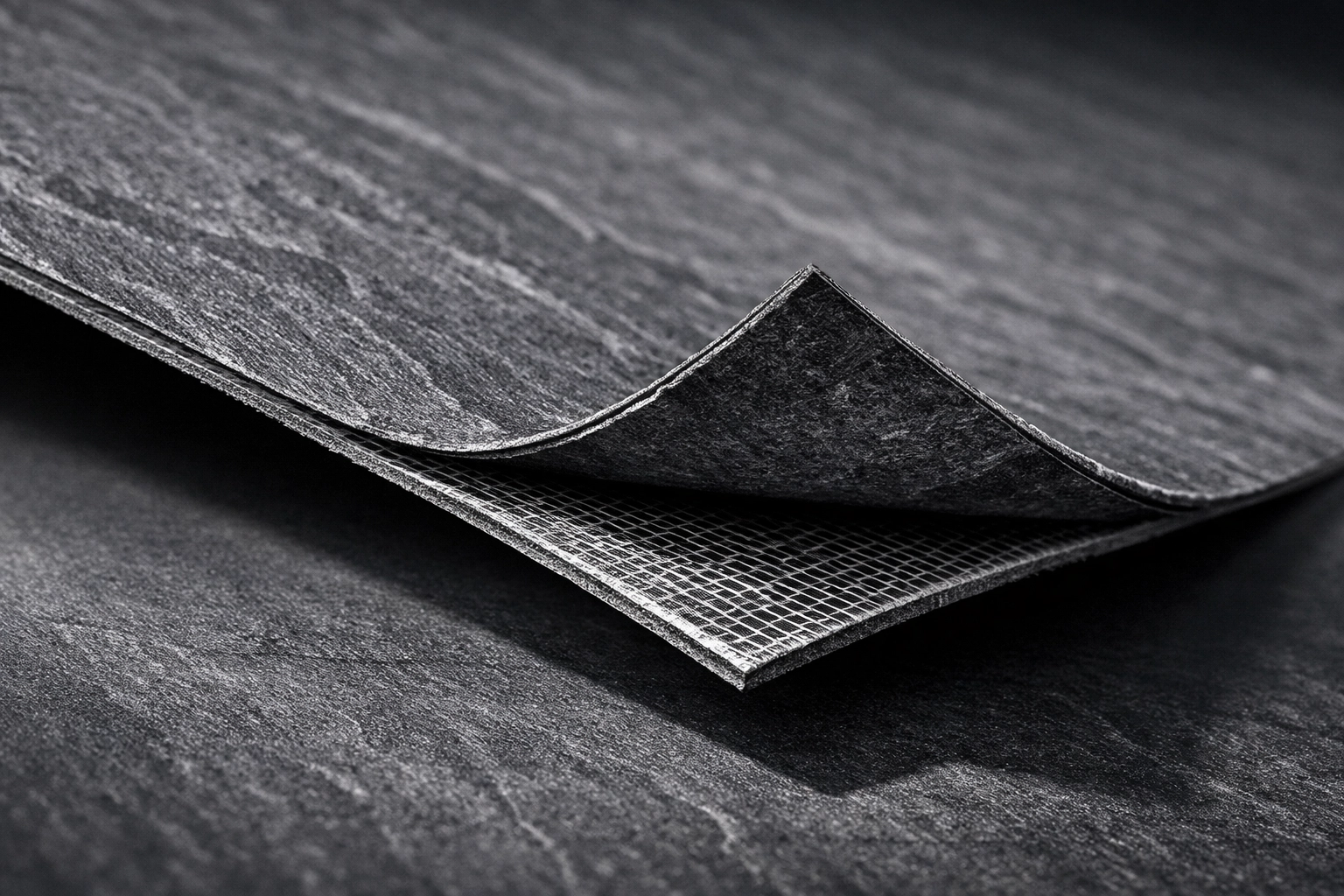 Ultra-thin 2mm slate grey flexible natural stone panel showing high flexibility and fiberglass backing.
