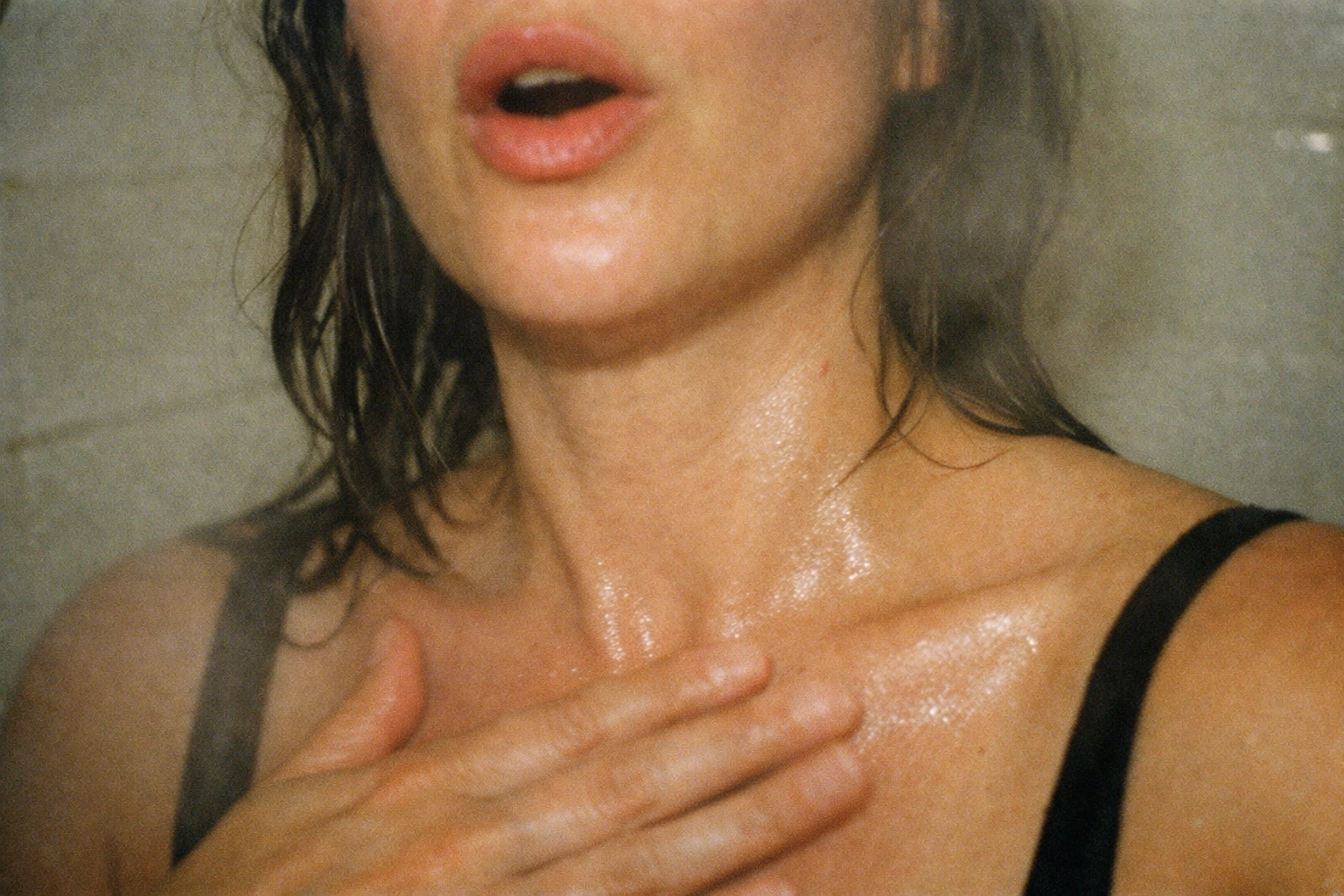 Raw close-up of throat and collarbone, mouth slightly open as if humming—tiny motion blur that almost looks like the vibration itself.