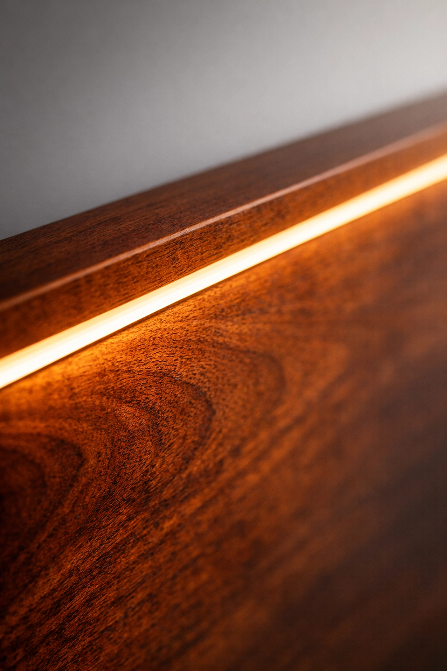 Warm linear LED strip highlighting the natural wood grain of a mahogany closet panel.