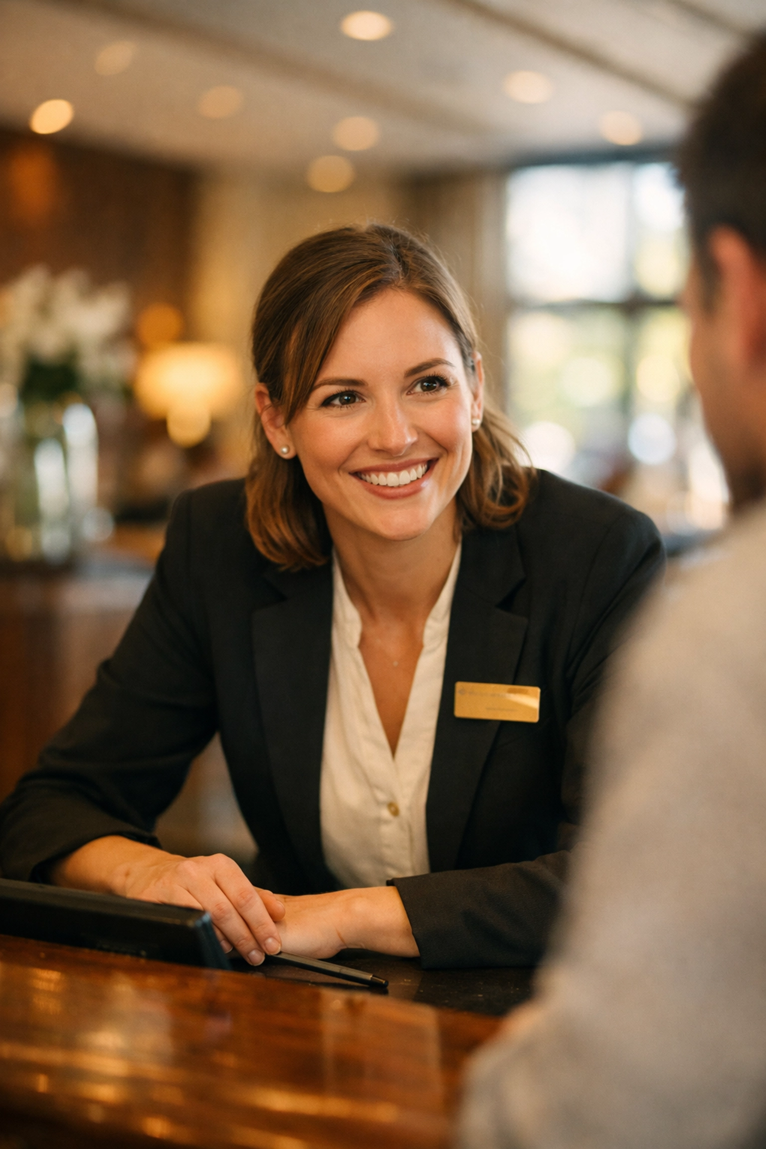 Hotel front desk staff member warmly greeting guest, demonstrating personal hospitality service